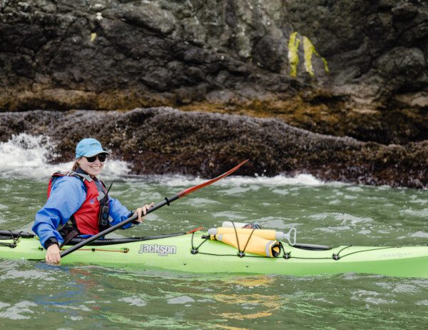 Kayaker circumnavigating Angel Island looking at the barnacles on the Sea Cliffs.