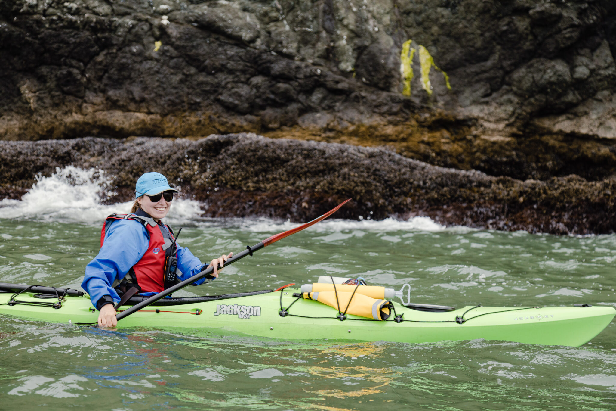 Kayaker circumnavigating Angel Island looking at the barnacles on the Sea Cliffs.