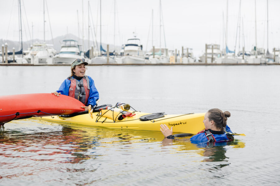 2 girls learning how to upright their flipped kayak during a class with Sea Trek during a class in Sausalito, CA
