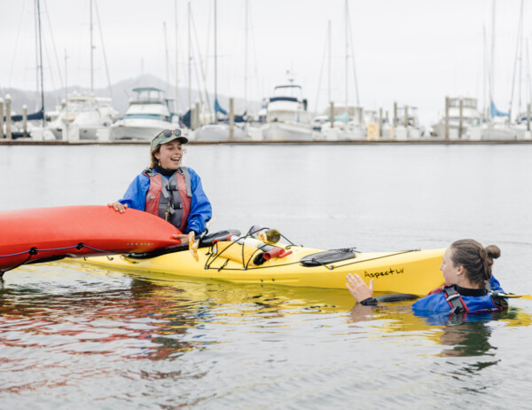 2 girls learning how to upright their flipped kayak during a class with Sea Trek during a class in Sausalito, CA