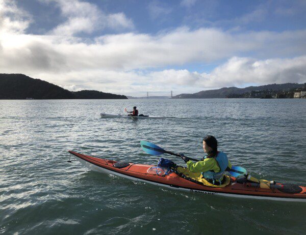 2 kayakers in the SF bay with the Golden Gate Bridge in the distance